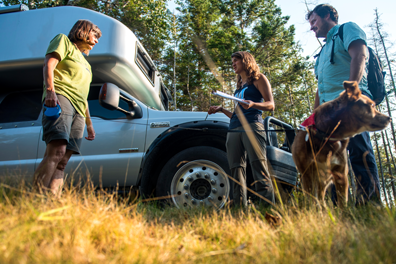 A group of grads standing in front of a car while doing fieldwork