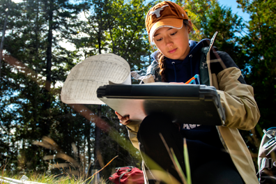 A person writing on a clipboard while doing fieldwork
