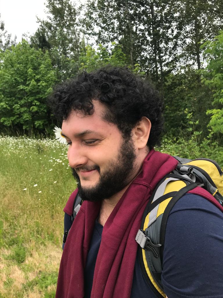 Photo of Daniel Balderrama in a field of wildflowers, with trees in the background