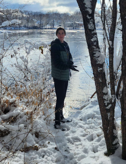 Kit Carpenter standing on a snowy shoreline in the woods