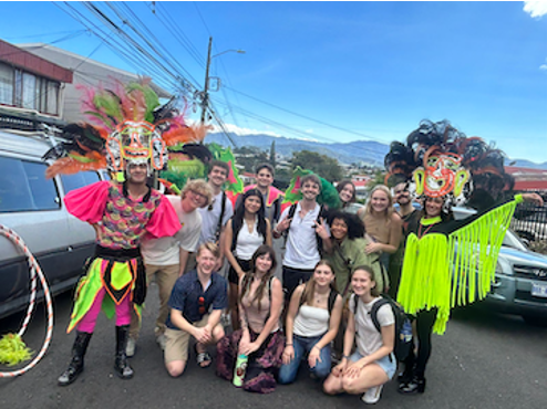 Group of people including two in indigenous costumes on a street in Costa Rica
