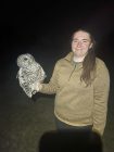 Morgan Anderson smiling at the camera and holding a barred owl