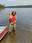 Leo Villacís standing knee-deep in a lake, wearing hip waders and a life vest