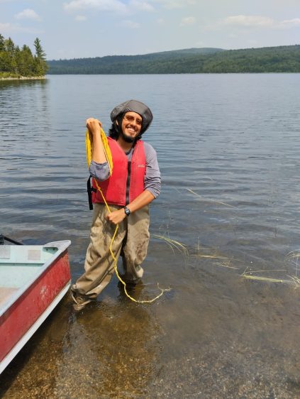 Leo Villacís standing knee-deep in a lake, wearing hip waders and a life vest