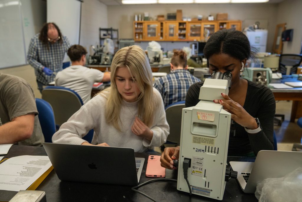 Students in Jared Talbot's class look through microscope